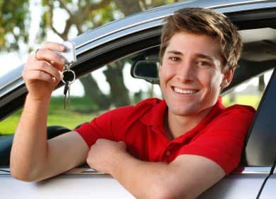teen boy sitting in the driver seat holding keys to his car