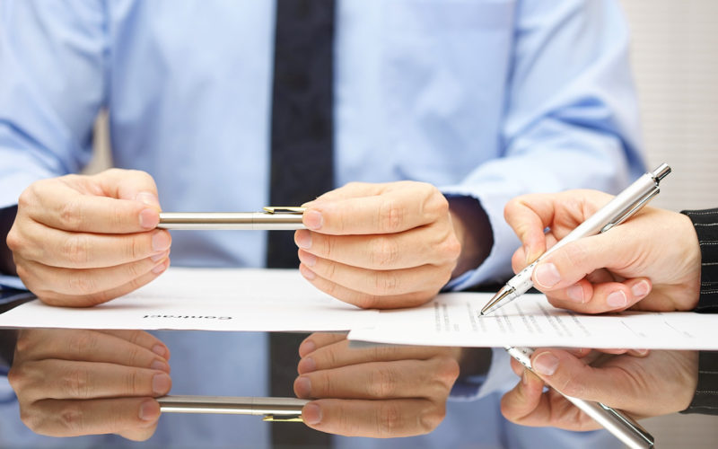 two people reading and signing a contract