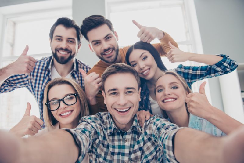 Self portrait of economists, students, financiers, lawyers in casual outfit showing thumb up with fingers shooting selfie on front camera with joyful cheerful expression having leisure, timeout