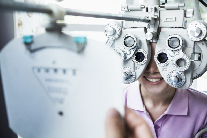Close-up of optometrist doing an eye exam on young woman
