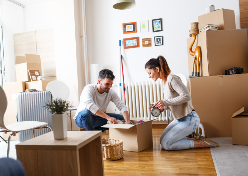 Young couple unpacking cardboard boxes at new home.Moving house.