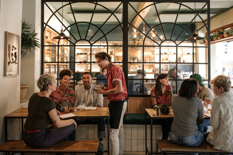 Waiter taking orders from customers sitting in a bistro