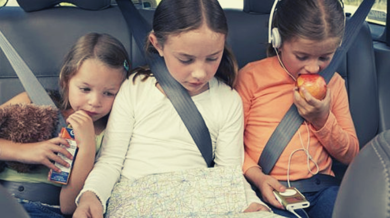 three young girls in the backseat of a car on a road trip