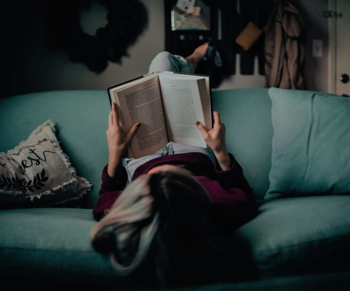 person laying on back reading book