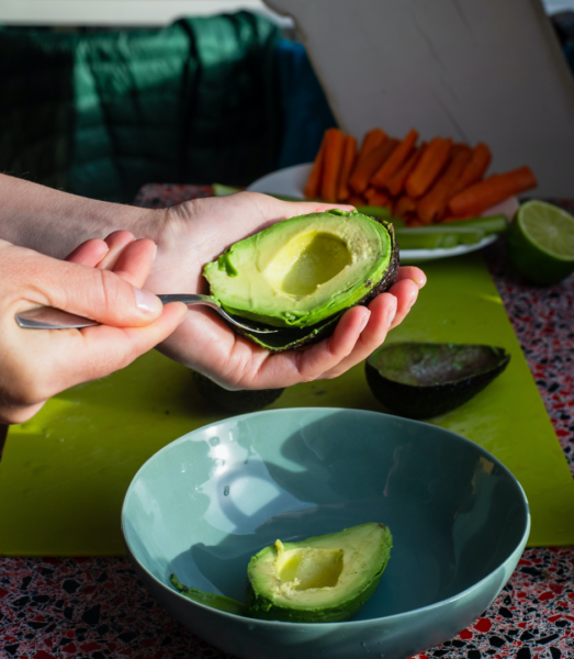 hands scooping avocado into bowl